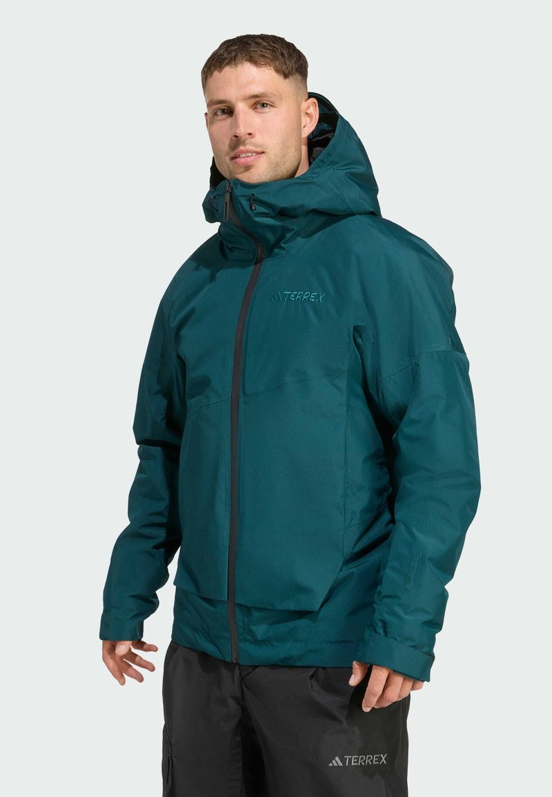 Türkisfarbene, wasserdichte Jacke mit Kapuze, vorderem Reißverschluss und verstellbaren Ärmeln. Enthält ein Logo auf der Brust und besticht durch ein elegantes, schlankes Design.