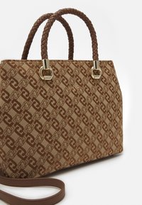 Brązowa i beżowa torebka w wzory z plecionymi uchwytami, złotymi akcentami i odpinanym paskiem na ramię na białym tle.