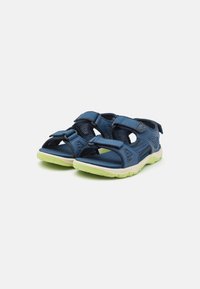Blå multi-rem sandaler med mesh-paneler och kardborrestängningar; har en vadderad innersula och en ljusgrön gummisula.