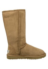 Korkeat tan-suede saappaat, joissa on pyöreä varvas, näkyvät saumat ja tasapohjainen kumipohja. Sivulla on etiketti. Pehmeä tekstuuri.