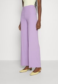 Lavender wijde broek met een gladde textuur en hoge taille, gecombineerd met gele puntige muiltjes.