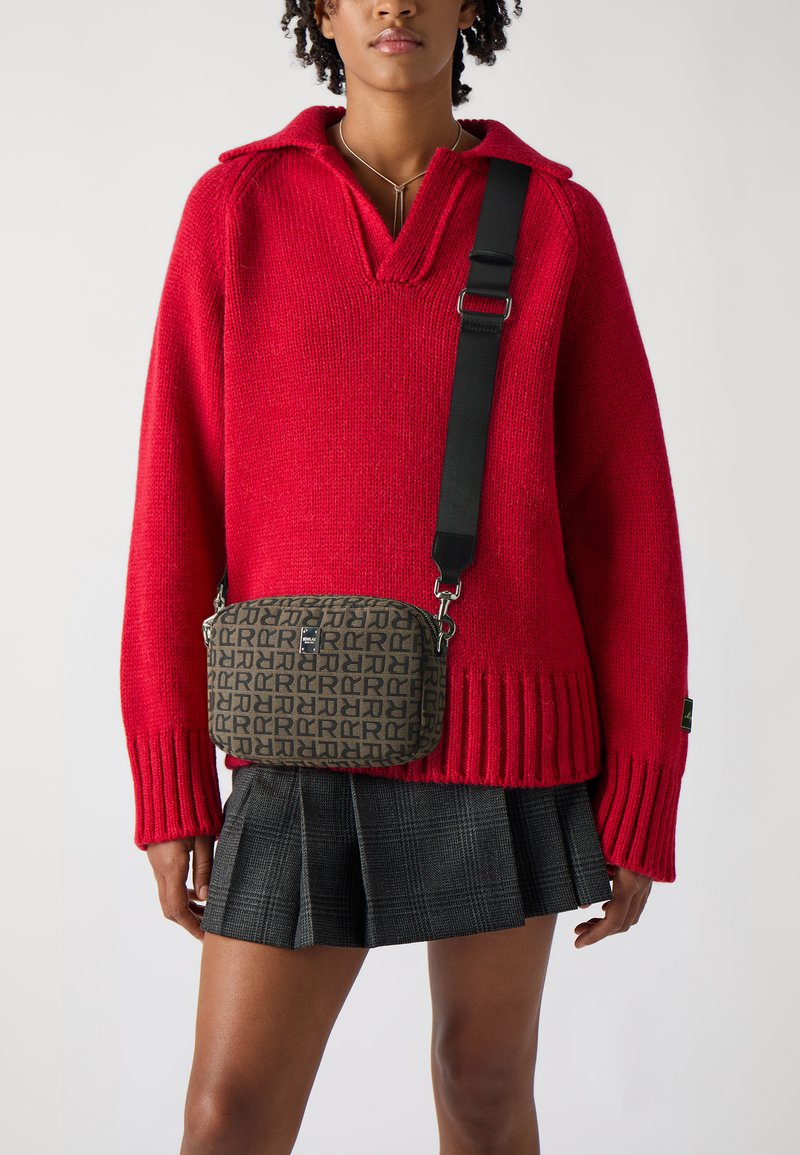 Rød strikket sweater med krave og ribbestrikket kant, parret med en brun mønstret crossbody taske og en sort ternet nederdel.