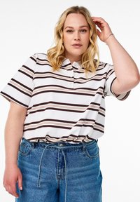 Polo rayé blanc avec des lignes marron et beige, doté d'un col et de manches courtes, associé à un jean en denim bleu.