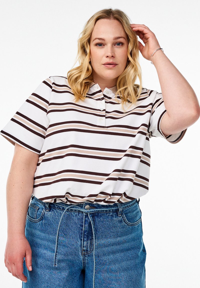 Polo rayé blanc avec des lignes marron et beige, doté d'un col et de manches courtes, associé à un jean en denim bleu.