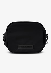 Čierna crossbody taška štvorcového tvaru vyrobená z textúrovanej tkaniny, s uzatváraním na zips a výrazným embosovaným logom na obdĺžnikovom pruhu.