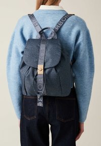 Zaino in pelle blu texturizzata con chiusura a pattina e spallacci con logo stampato. Presenta un gancio in tonalità dorata e lati arricciati.