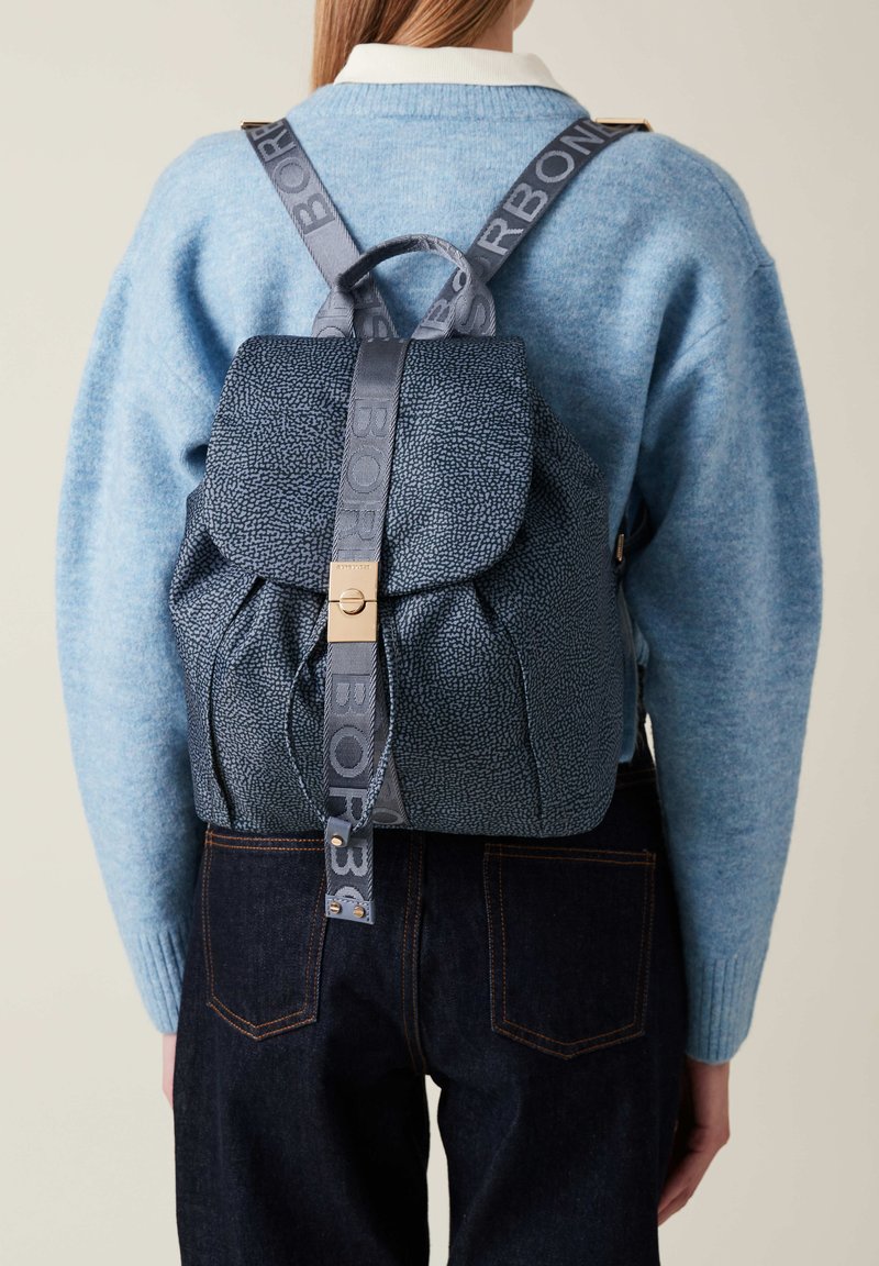 Zaino in pelle blu texturizzata con chiusura a pattina e spallacci con logo stampato. Presenta un gancio in tonalità dorata e lati arricciati.