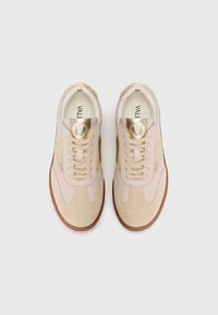Un paio di sneakers Valentino in pelle beige e oro con accentuazioni in suede e suole ovali in gomma marrone, viste dall'alto su sfondo bianco.
