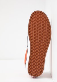 Gummisåle i orange og hvid med et hexagonalt mønster for greb og holdbarhed. Siden har sort og orange paneler.