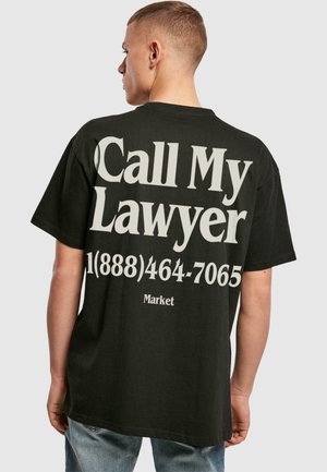Sort bomulds t-shirt med stort hvidt tekst på ryggen, som siger "Ring til min advokat" med telefonnummer og ordet "Marked." Casual pasform.