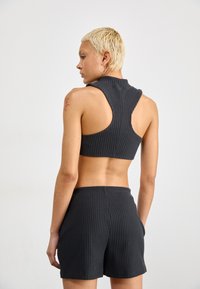 Grijze, geribbelde sportset met een mouwloze crop top en bijpassende shorts. Opvallend uitgesneden ontwerp en zachte textuur met een elastische tailleband.