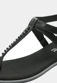 Sandal nero con design a T, caratterizzato da perline nere lucide lungo la fascia. Suola imbottita morbida e suola flessibile.