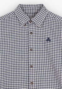 Camisa de cuadros en azul marino y blanco con cuello extendido, botones marrones y un pequeño logo bordado en el lado izquierdo.