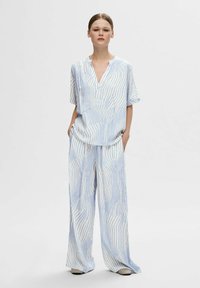 Top leggero a righe blu e bianche con scollo a V e maniche corte, abbinato a pantaloni larghi e comodi con righe coordinate.