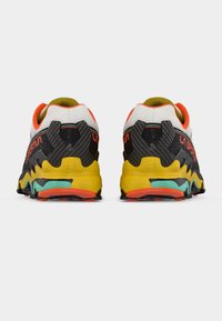 Πολύχρωμα παπούτσια για τρέξιμο σε μονοπάτια με επάνω μέρος από δίχτυ σε λευκό και μαύρο, κίτρινη σόλα και πορτοκαλί λεπτομέρειες. Διαθέτουν εξωτερική σόλα με υφή για καλύτερη πρόσφυση.