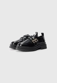 Black patent leather shoes with two adjustable straps and gold buckles, featuring a chunky black sole and pull tab at the back.