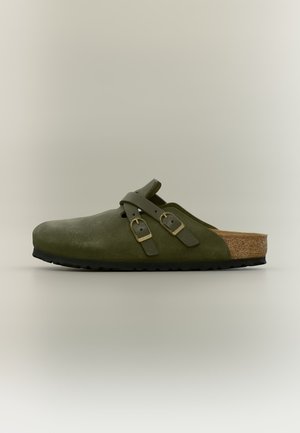 Lukkede olivengrønne slip-on sandaler med to justerbare spænderem og en korkfodseng med sort sål.