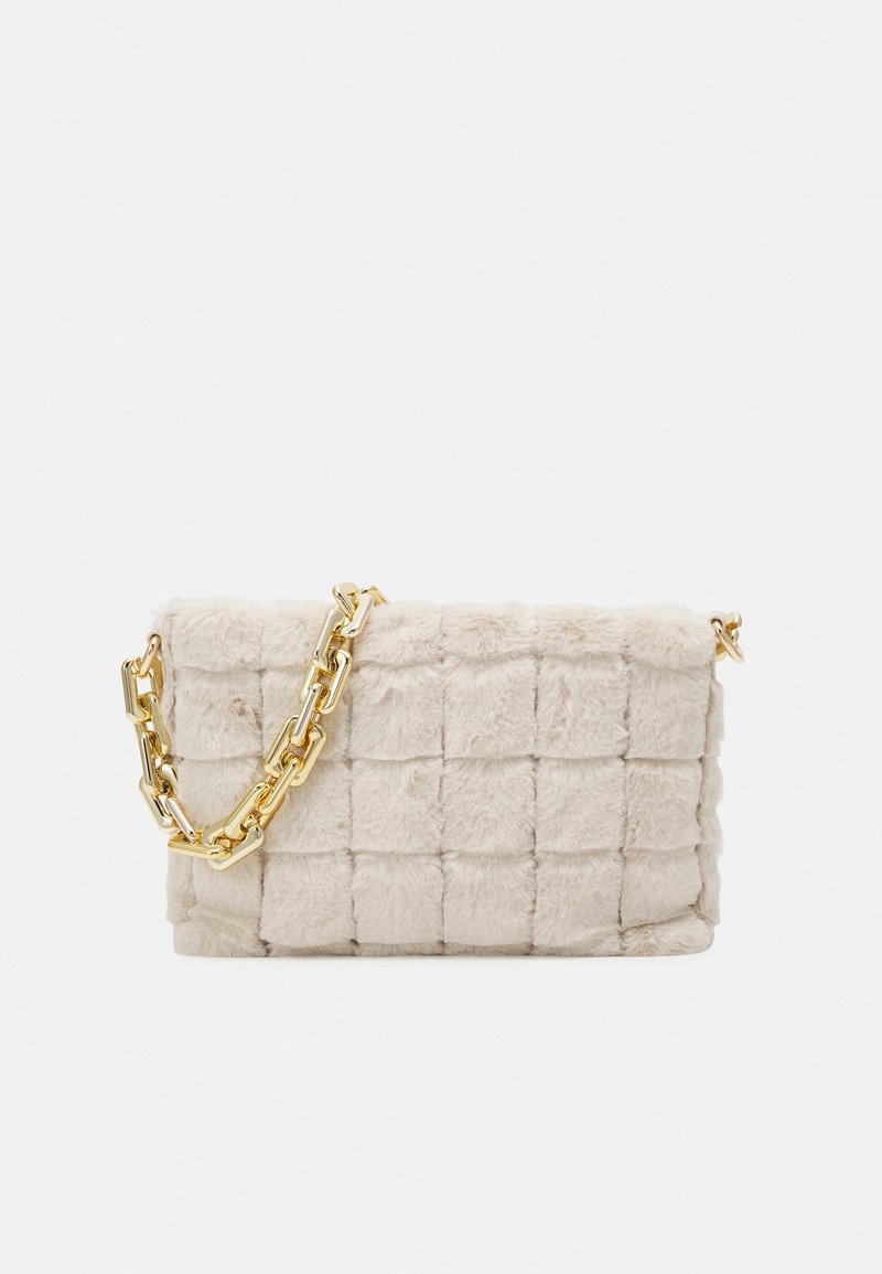 Sac à main en fausse fourrure matelassée beige avec une courte anse chaîne dorée épaisse sur fond blanc.