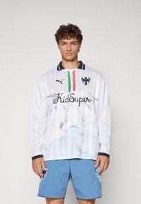 Weißes Langarm-Jersey mit horizontalen Streifen, mehrfarbigen Akzenten am Kragen und einem Wolkenmuster; verfügt über ein Logo und Text auf der Vorderseite.