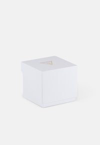 Balta kartoninė dėžutė su tekstūriniu paviršiumi, kvadrato formos, sulankstoma dangteliu ir auksiniu trikampio logotipu viršuje. Minimalistinis dizainas.