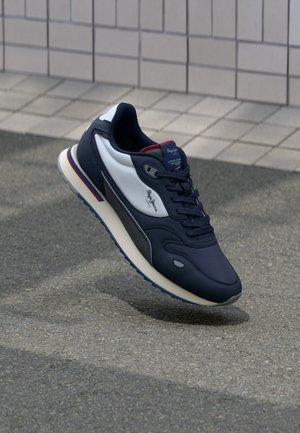 Marineblaue Sneakers mit weißen Akzenten und einer strukturierten Oberfläche. Verfügt über eine gepolsterte Sohle, Schnürverschluss und Branding auf der Zunge.