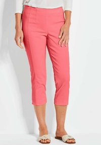Roze cropped broek van een gladde stof, met een aansluitende taille en schuine zakken, gecombineerd met lichte sandalen.
