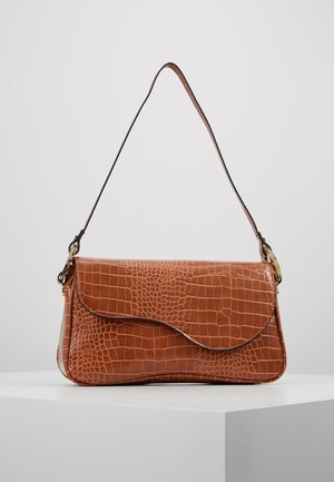 Brown faux crocodile leather shoulder bag with curved flap and slim adjustable strap resting on white pedestal.