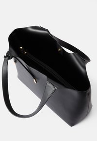Μαύρη δερμάτινη τσάντα tote με λεία επιφάνεια, δύο ανθεκτικά χερούλια και ανοιχτή κορυφή. Διαθέτει μια κλειστή τσέπη με φερμουάρ στο εσωτερικό και μεταλλικές λεπτομέρειες.