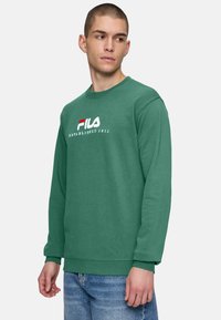 Groene katoenen sweatshirt met ronde hals, geribbelde manchetten en zoom. Bevat het witte en rode Fila-logo en de tekst "OPGERICHT IN 1911".