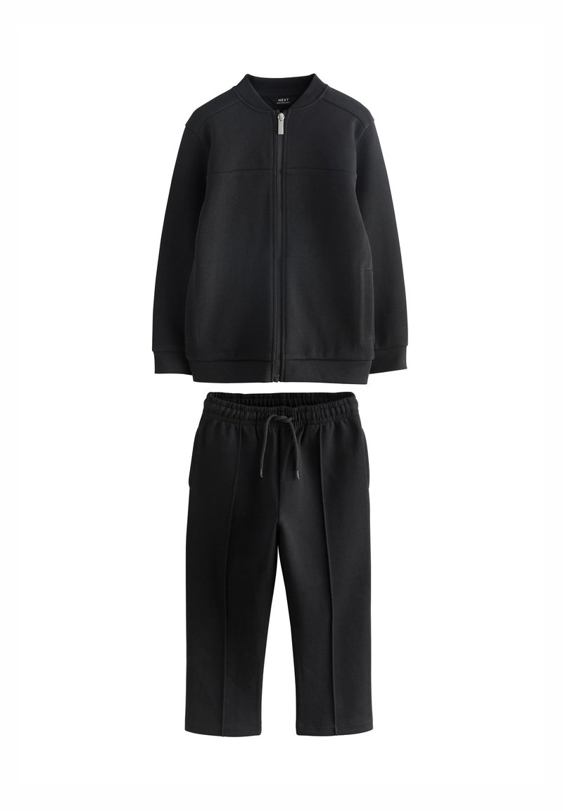 Schwarze Jacke mit Reißverschluss, geripptem Kragen und zwei Taschen, kombiniert mit schwarzen Hosen mit elastischem Bund, geradem Bein und Seitennaht.