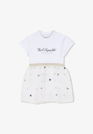 Bela bombažna obleka s kratkimi rokavi in prozorno tutu krilom. Na tutu krilu so razporejene srebrne in črne črke "KARL". Pas je poudarjen.