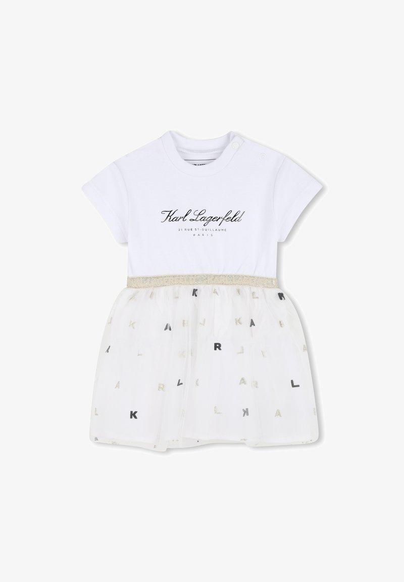 Λευκό βαμβακερό φόρεμα με κοντά μανίκια, που διαθέτει διαφανές τούλινο φόρεμα. Ασημένια και μαύρα γράμματα "KARL" διασκορπισμένα στο τούλι. Ζώνη με τονισμένη μέση.
