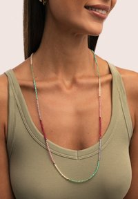Beaded necklace featuring multicolored glass beads in turquoise, pink, green, and gold accents, displayed on a light green tank top.