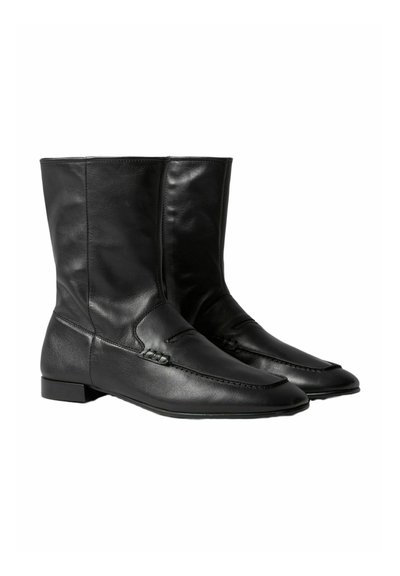 Botas de tobillo de cuero negro con un acabado liso, que presentan una puntera redondeada y un detalle de costura decorativa en la parte superior. Tacón bajo de bloque.