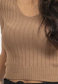 Top en tricot côtelé marron avec un col rond et des manches courtes, présentant un motif texturé et une silhouette ajustée.