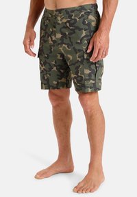 Maskovacie kraťasy v zelených a hnedých odtieňoch s gombíkovým zapínaním, viacerými vreckami a voľným strihom. Vyrobené z ľahkej tkaniny.