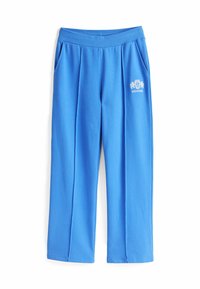 Niebieskie dresowe spodnie z bawełny z bocznymi kieszeniami, elastycznym pasem, z przodu plisy i białym logo po lewej stronie uda.