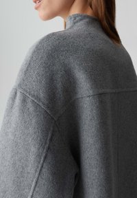 Grijze wolmix pullover met een hoge kraag, voorzien van een gestructureerde afwerking en afgeknipte schoudernaden voor een relaxte pasvorm. Glad en warm materiaal.