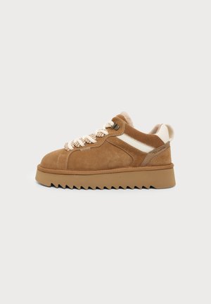 Brauner Wildledersneaker mit dicker Sohle, weißen Akzenten, gemusterten Schnürsenkeln und gepolstertem Kragen, im Seitenprofil vor einfachem Hintergrund gezeigt.