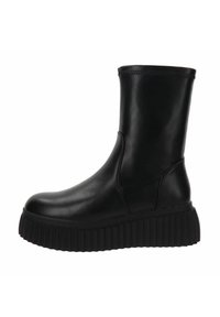 Botines negros de tobillo hechos de cuero suave con punta redondeada, parte superior elasticada y suela gruesa estriada para aumentar la altura y ofrecer soporte.