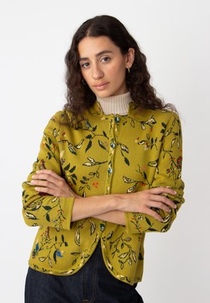 Green knitted cardigan with floral patterns, round neckline, button closure, and three-quarter sleeves. Features blue buttons and textured fabric.