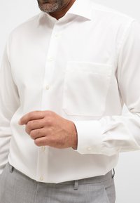 Witte overhemden met lange mouwen, een borstzak en knoopsluiting aan de voorkant. Gladde stof en klassiek kraagontwerp.