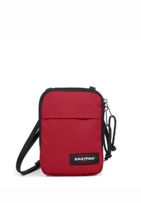 Borsa a tracolla rossa in tessuto con zip superiore, tasca frontale, bordo nero, tracolla regolabile e patch del logo Eastpak sulla parte frontale.