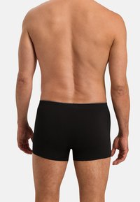 Černé boxerky vyrobené z hladkého materiálu, přiléhavý střih, s těsným pasem a minimálním švem, nabízející čistou estetiku.