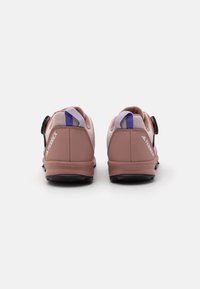Chaussures de sport rose et blanche avec tige en maille, semelle en caoutchouc solide et fermeture à molette réglable ; présente une marque sur le talon et sur le côté.