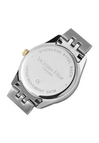 Reloj de acero inoxidable con una correa plateada, caja redonda, corona con acentos dorados y detalles grabados en la parte trasera, con una clasificación de 3ATM para resistencia al agua.