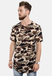 Kamouflage t-shirt i bomull; har jordnära toner av brunt, beige och svart; korta ärmar, rundad hals och en böjd nederkant.