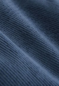 Primo piano di tessuto in velluto a coste blu scuro che mostra una texture morbida e un motivo a coste parallele.