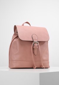 Rosa läderryggsäck med klafflock, silverfärgad spänne, dragsnörning och bärhandtag, visad på en vit yta.