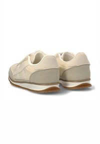 Zapatillas deportivas beige con un upper sintético suave, cuello acolchado y acentos grises texturizados. Presentan una suela de goma para mayor tracción.